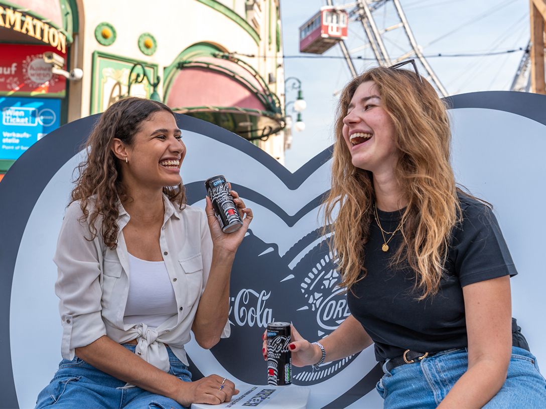 Zwei Personen auf der Bestie-Bank Platz mit dem brandneue Coca-Cola OREO® Zero Sugar