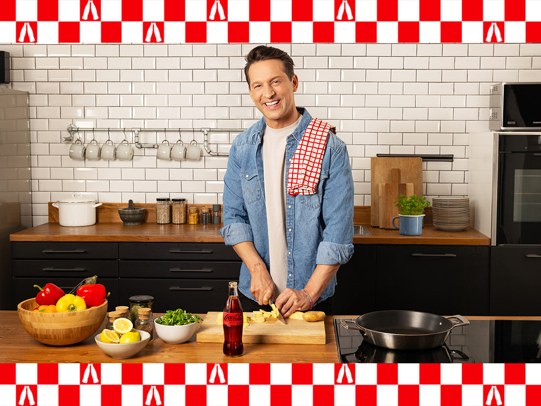 A bottle of Coca-Cola zero sugar and a full glass is on a table. Beside it are two plates of pizza.
