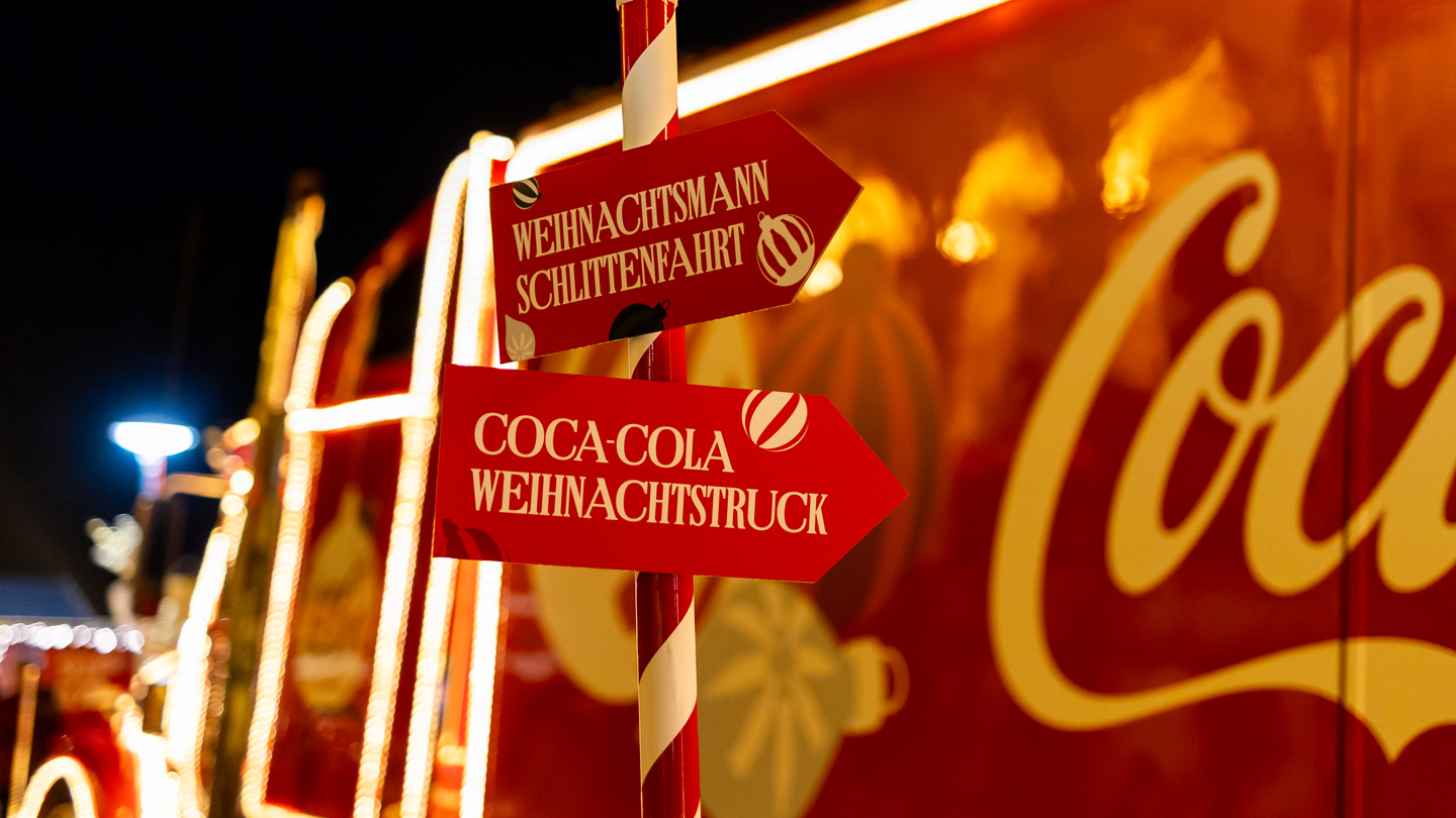 Ein Schild, auf dem der Weg zum Coca-Cola Weihnachtstruck gezeigt wird