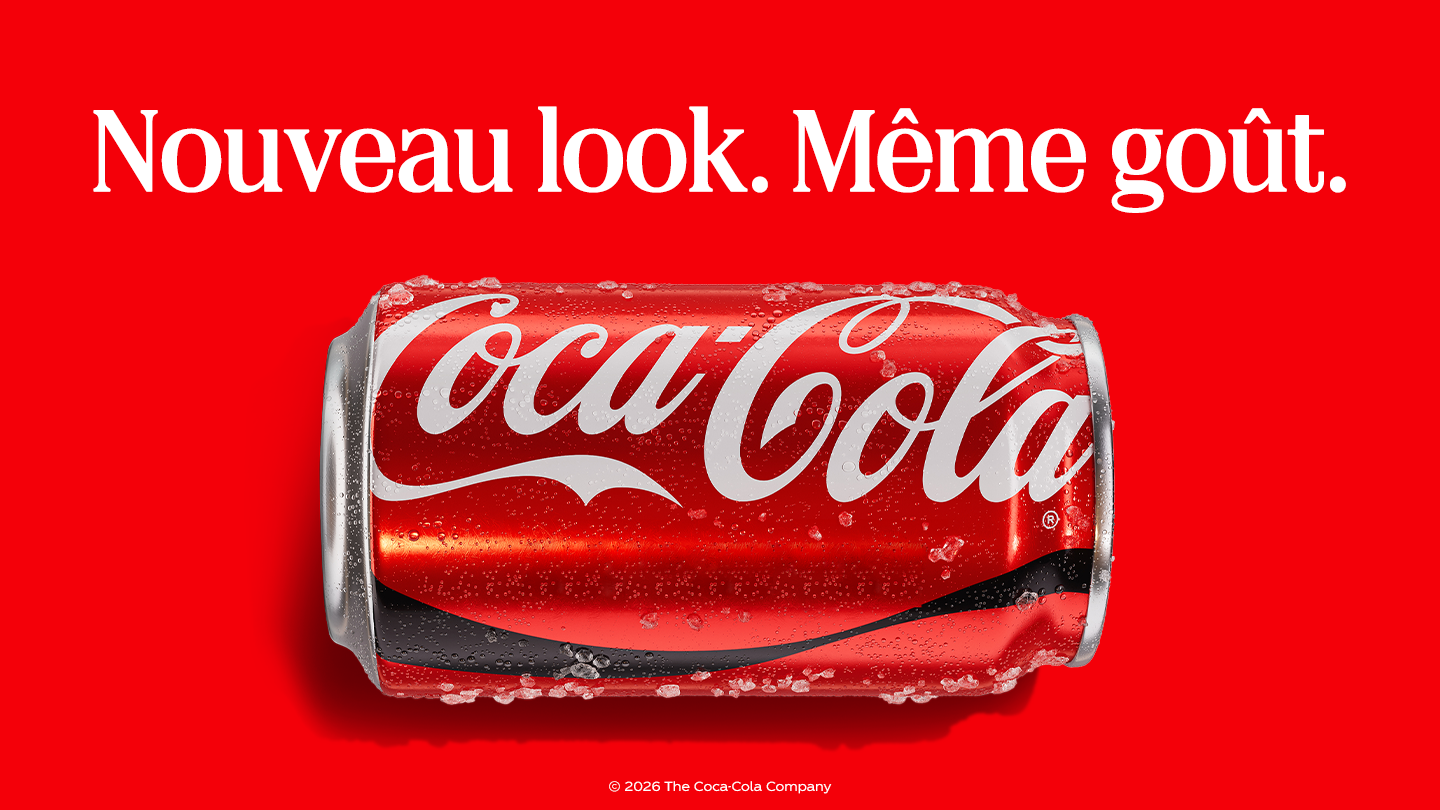 Canette de Coca-Cola rouge couchée à l’horizontale sur un fond rouge vif, couverte de gouttes d’eau et de glace. En haut, le texte blanc : « Nouveau look. Même goût. » En bas, la mention : « © 2026 The Coca-Cola Company ».