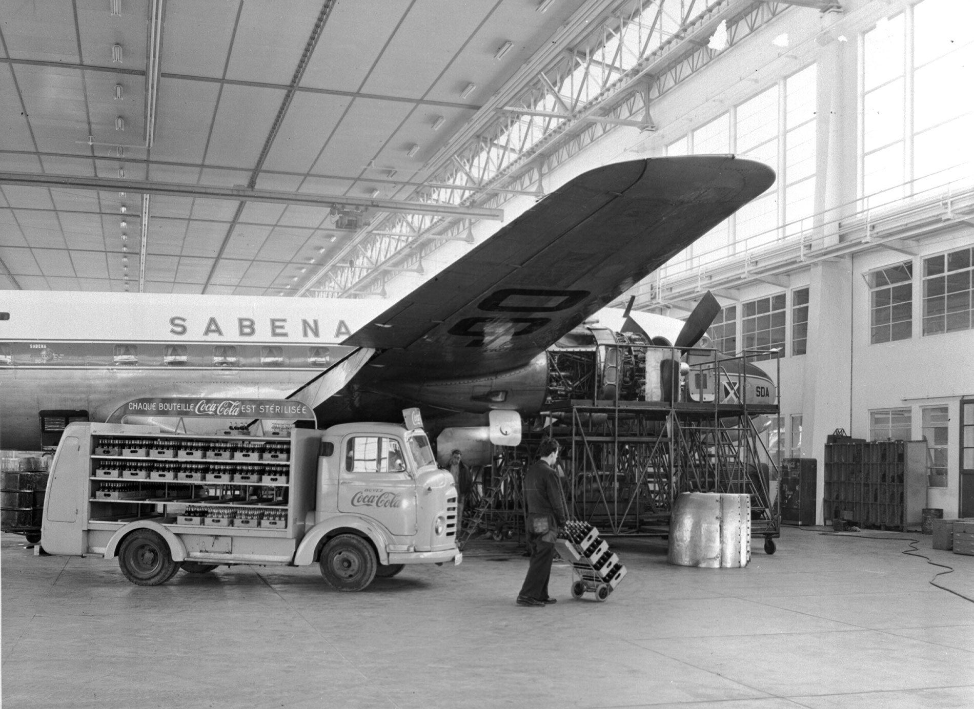 Foto van een Coca-Cola truck naast een Sabena vliegtuig