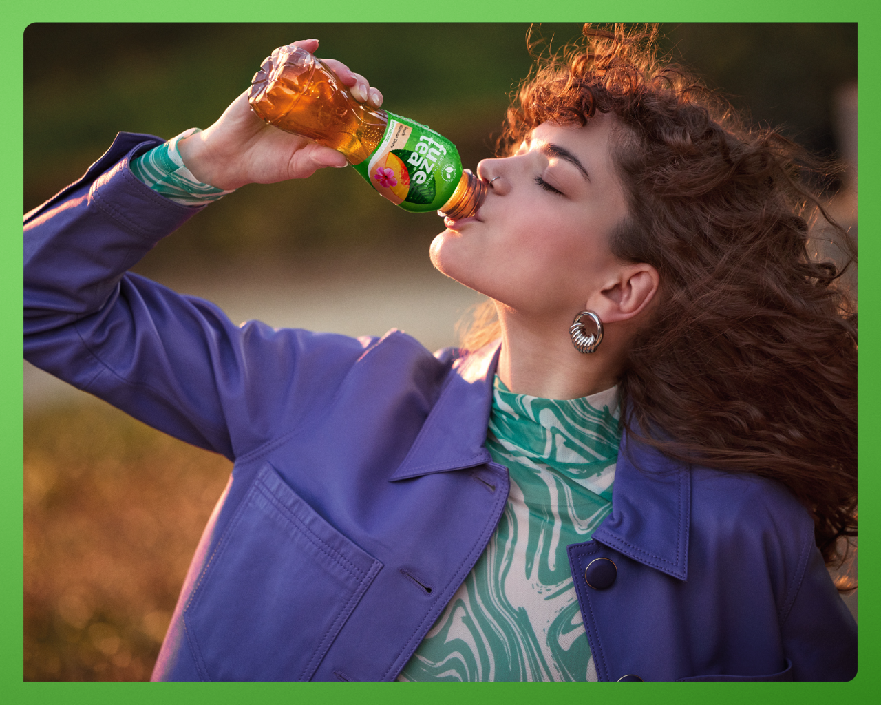 Jonge persoon die buiten staat en een fles fuze tea drinkt