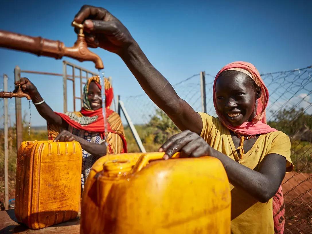 Afrikaanse vrouwen tappen water aan een kraan