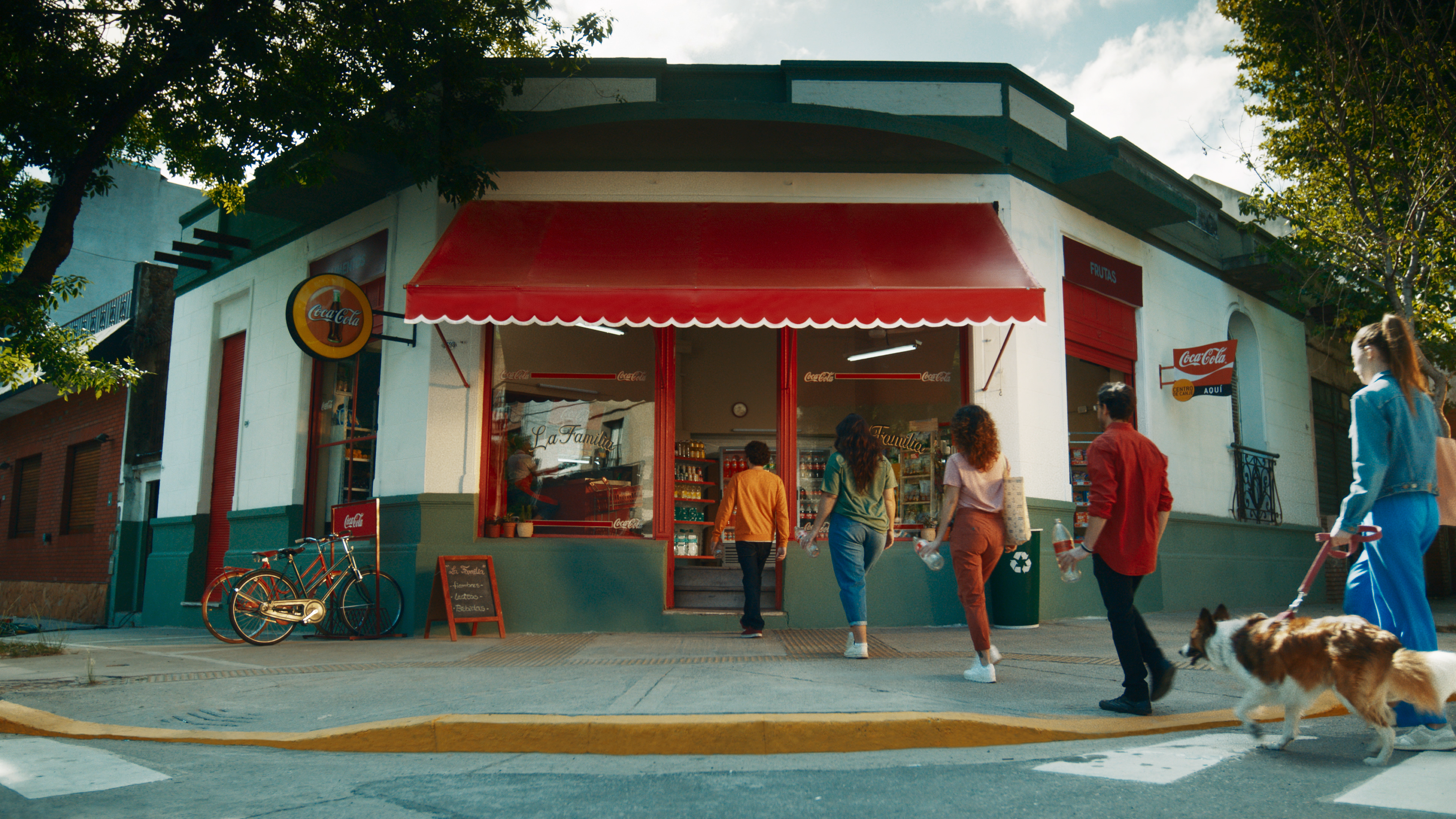 Personas entran a una tienda de barrio, con envases retornables de Coca-Cola en sus manos