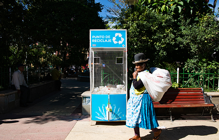 Una mujer pasa frente a un Contenedor, en una plaza