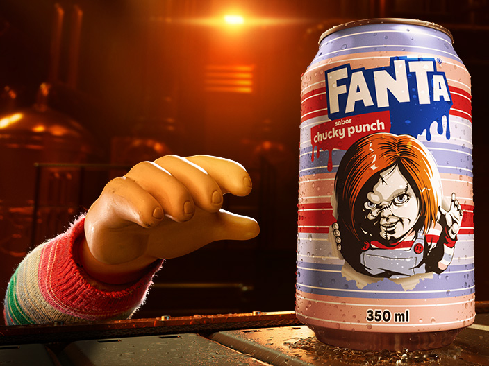 Logotipo azul da Fanta com efeito de gotejamento sobre um fundo laranja-avermelhado, com silhuetas de mãos escuras alcançando-o por baixo.