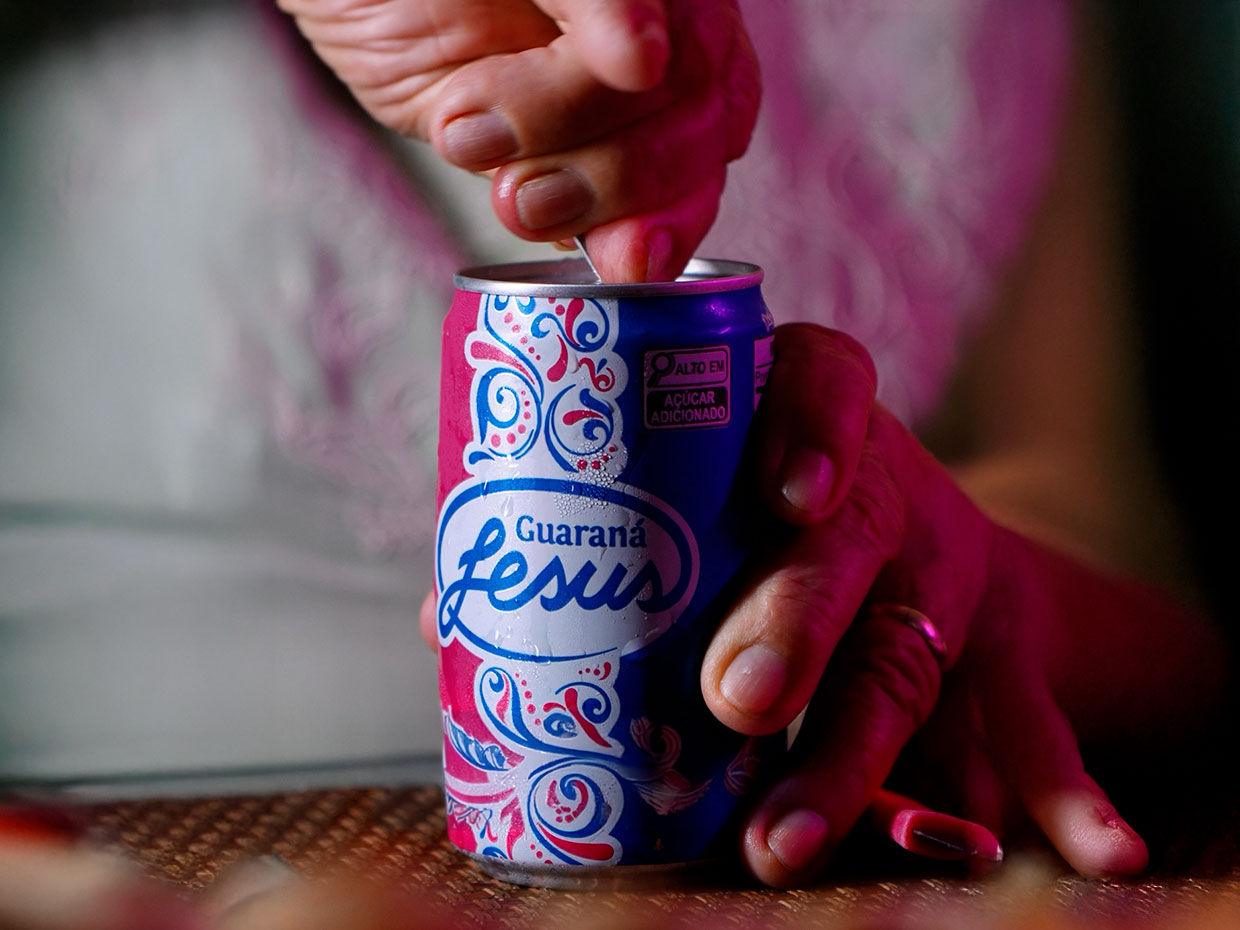 Mãos abrindo uma lata de Guaraná Jesus