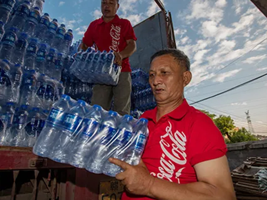 Two men unloading packages of bottled water from a truck