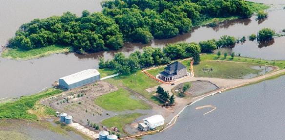 Two pieces of land surrounded by water, one is covered in trees and the other is mostly clear, flat land with several building structures in place