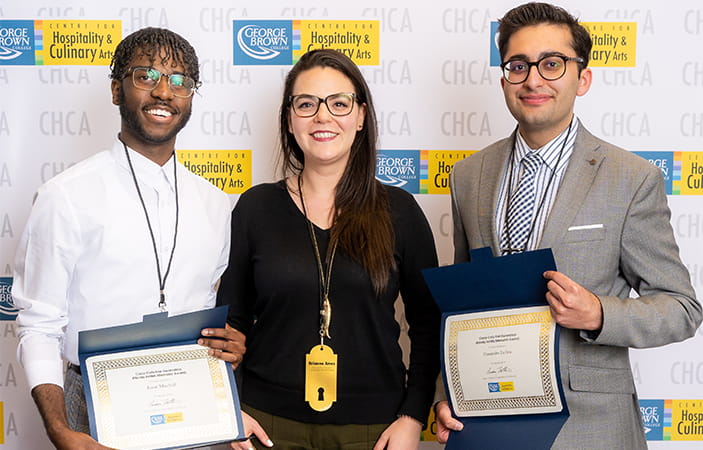 A group of people standing together holding College scholarship certificates 