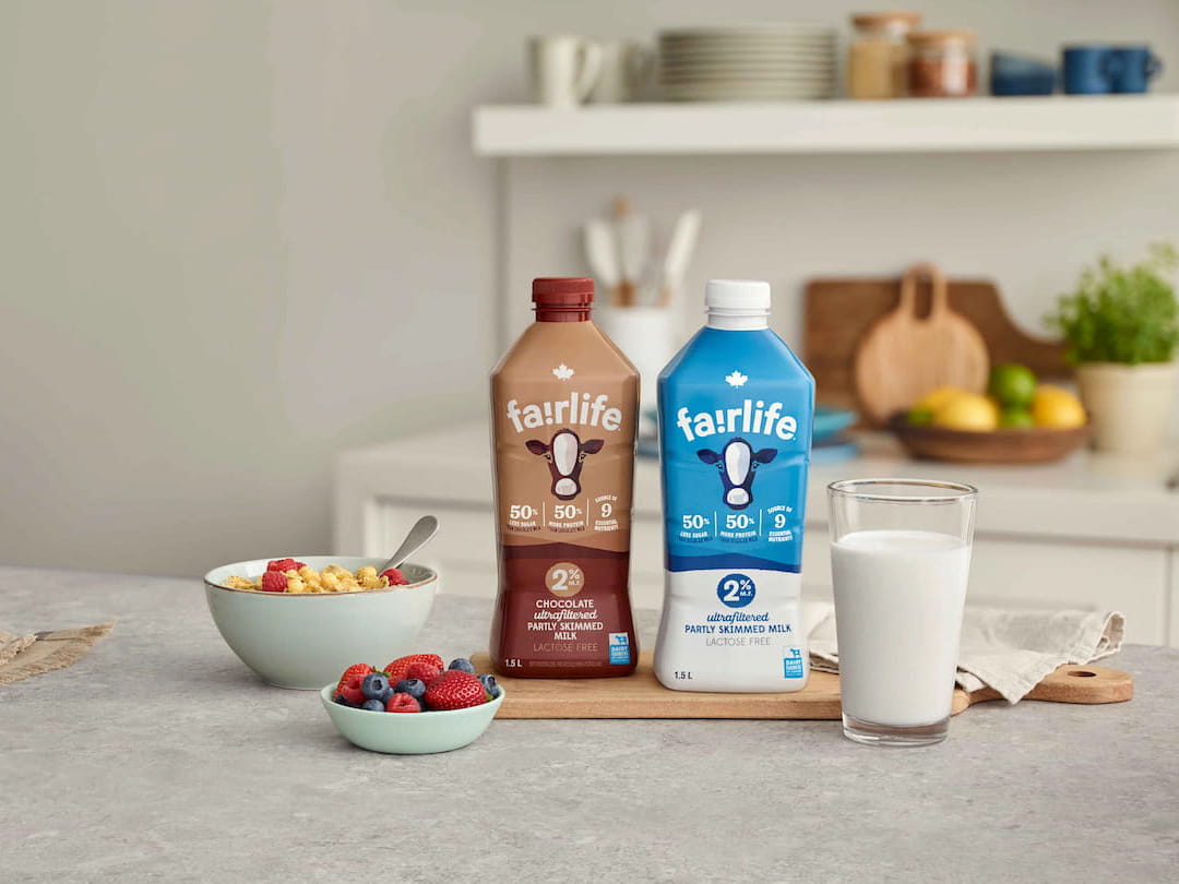 A fairlife® milk packaging, a glass of milk and a cereal bowl side by side