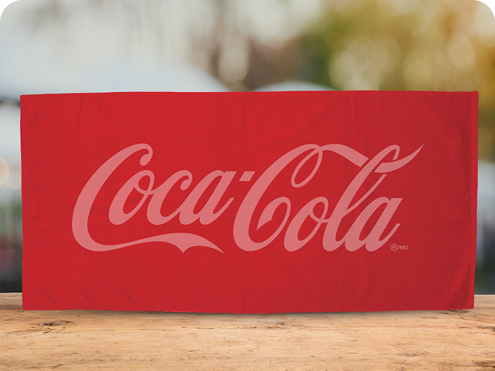A folded red Coca-Cola beach towel featuring a large, tone-on-tone script logo, offered as an Outdoor Activities prize.