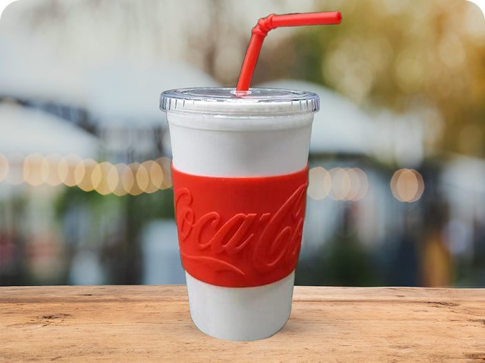 A reusable white tumbler with a red, textured Coca-Cola branded sleeve and a red straw, a prize in the summer contest.