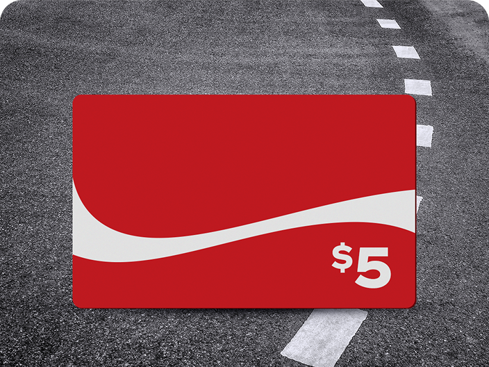 Une carte-cadeau prépayée rouge de 5 $ Coca-Cola, un prix du concours Voyage en voiture, sur un fond de route asphaltée.