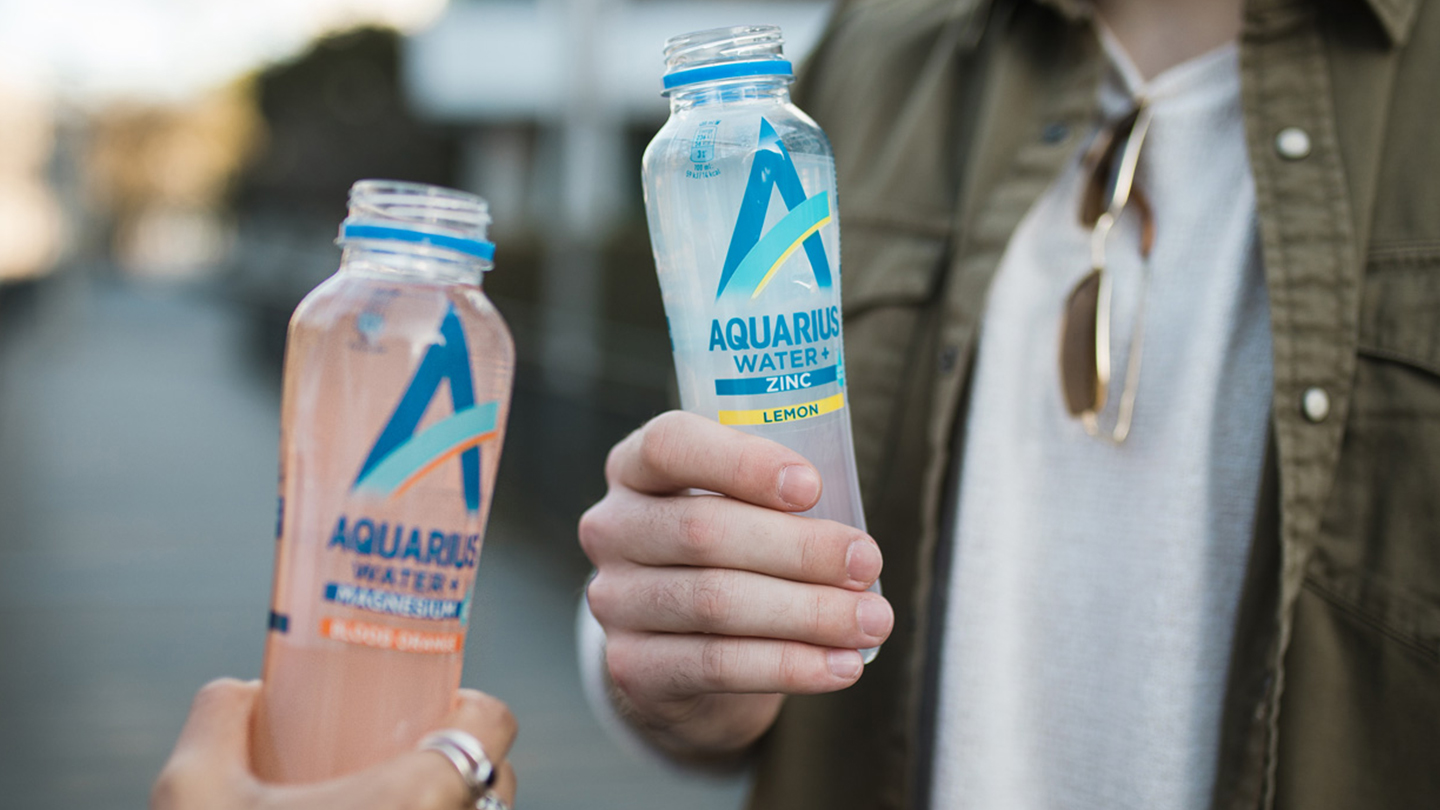Ein Mann und eine Frau stossen mit einer Flasche Aquarius Water an