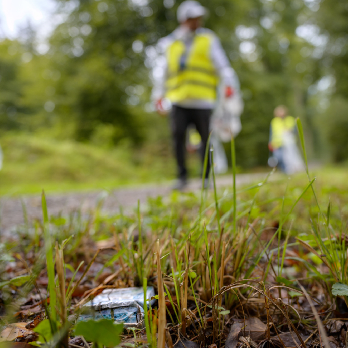 Zwei Personen befreien eine Wiese von Müll.