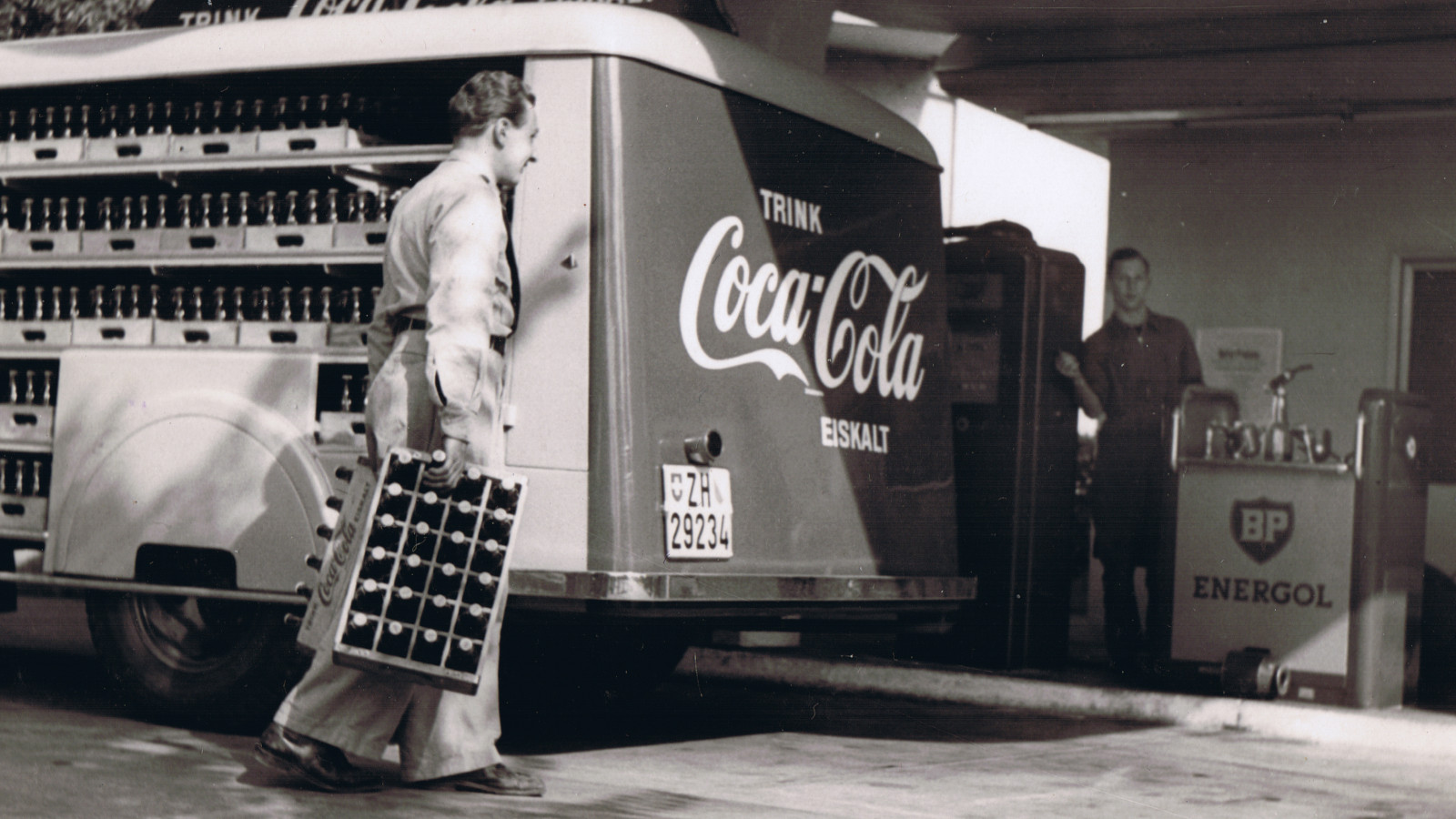 Historische Aufnahme eines Coca-Cola Lieferwagens bei einer Tankstelle in der Schweiz.