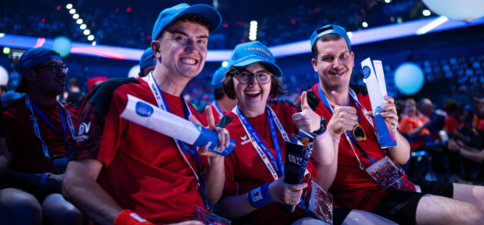 Drei Teilnehmende sitzen bei der Eröffnungsfeier der Special Olympics National Games im Publikum.