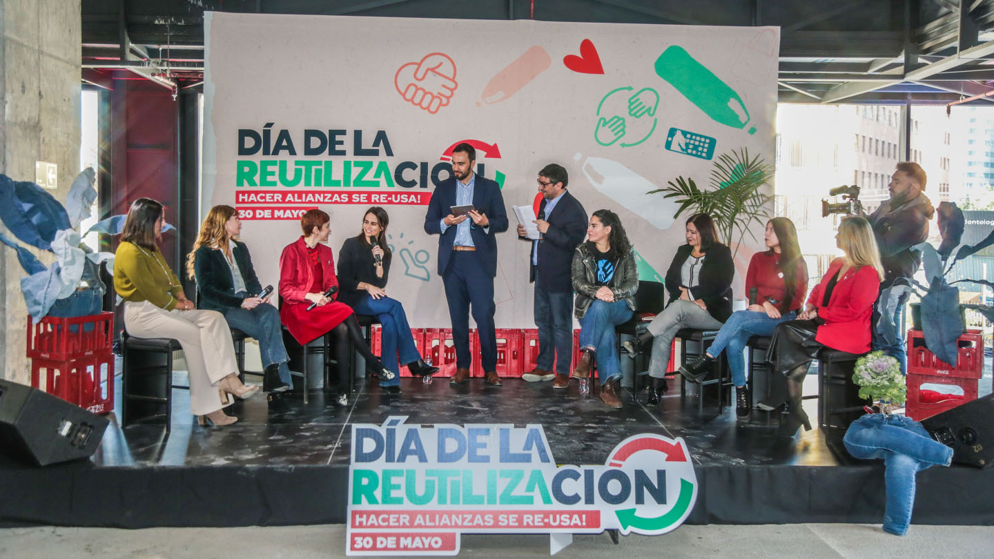 Fotografía de un grupo de personas en una oficina posando junto a un cartel que incluye un hashtag y las letras de la palabra "Aliados"