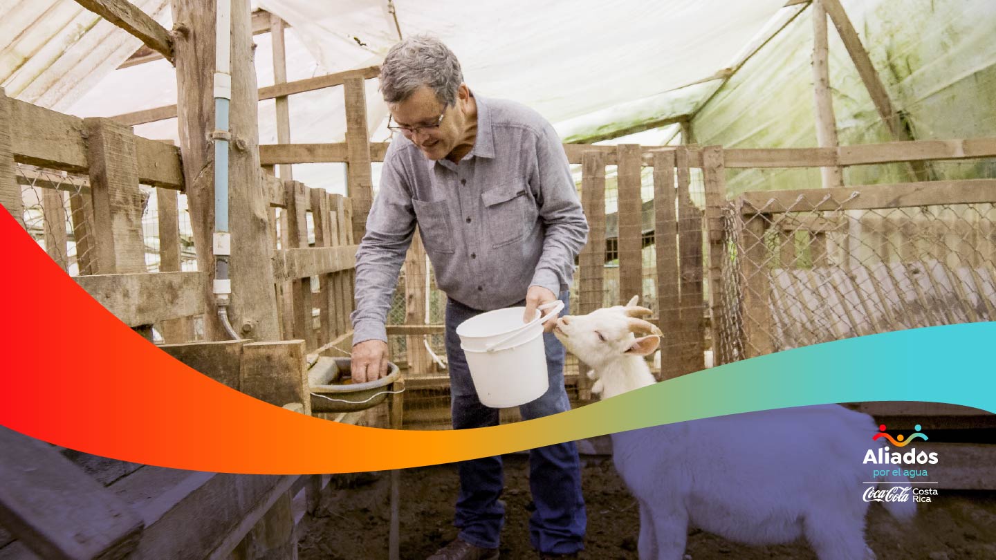 FOTOS PAÍSES Hombre sonriente con un balde de color blanco en la mano y una cabra a su lado