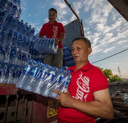 Two men unloading packages of bottled water from a truck