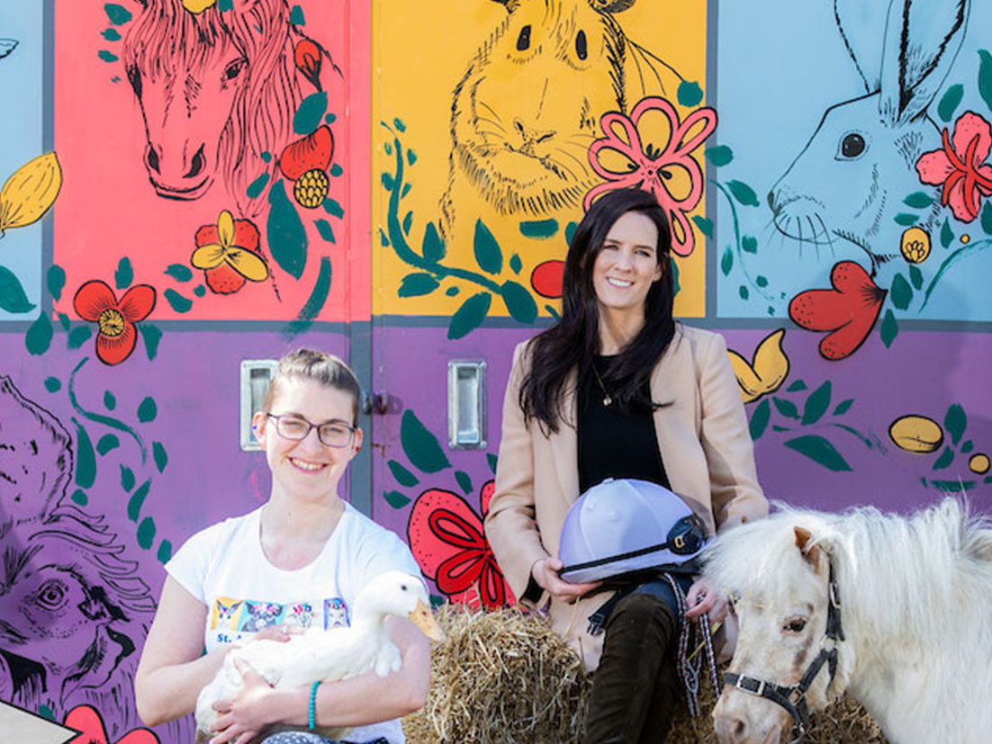 A group of women posing next to a pony