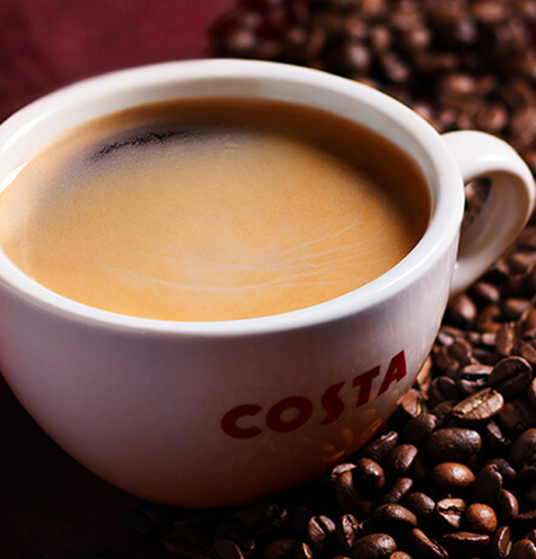 Mug of costa coffee placed in coffee beans