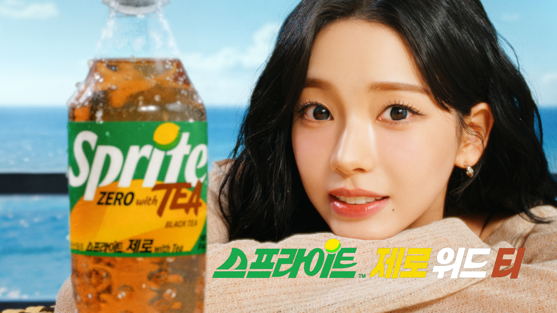 스프라이트 제로 위드 티 모델 카리나와 500ml PET 제품이 함께 배치된 이미지. 바다를 배경으로 카리나가 미소를 짓고 있으며, 우측 하단에는 제품 풀 네임인 스프라이트 제로 위드 티 가 기재되어있다.