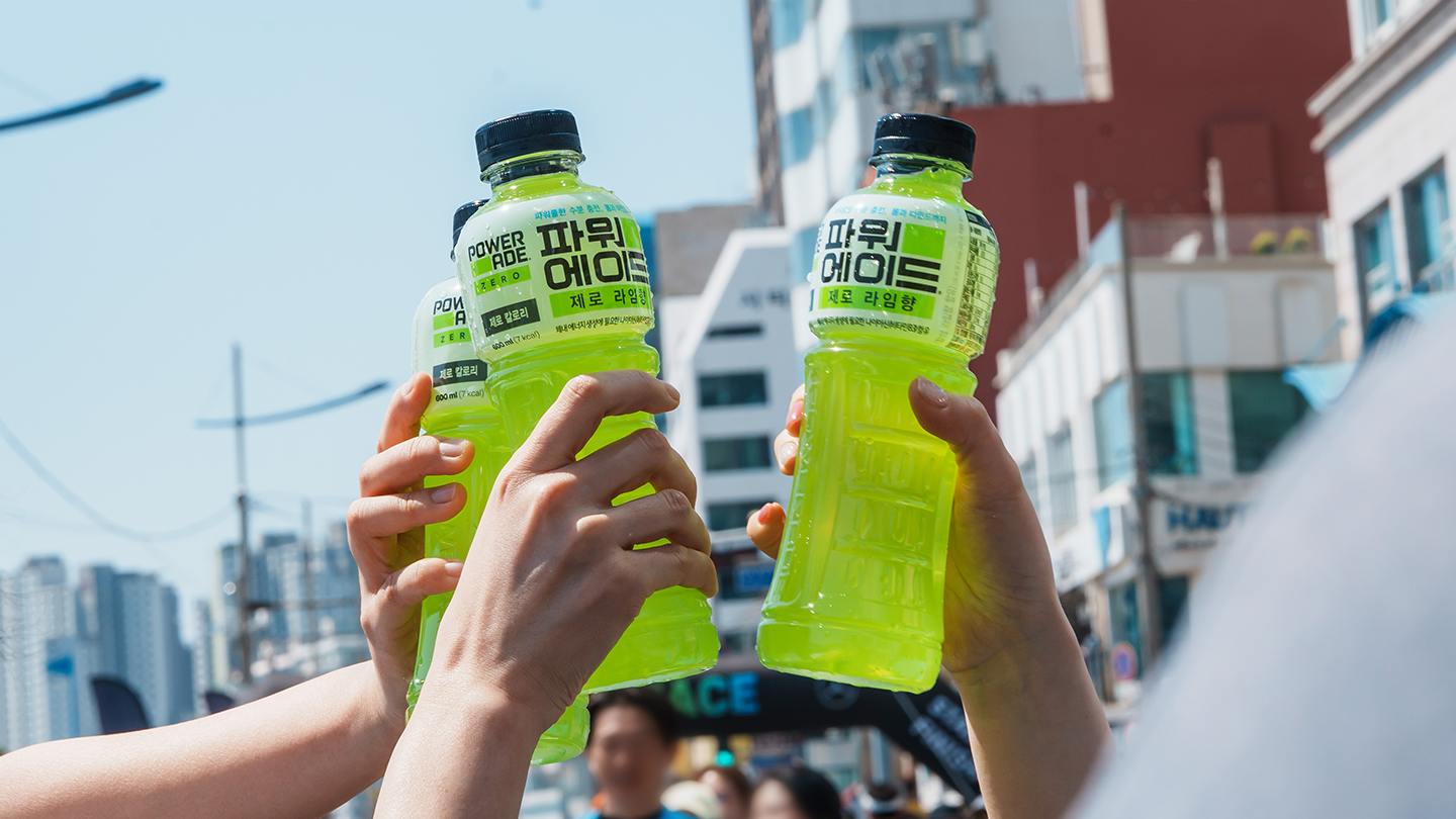마라톤 대회에 참가한 러너들이 수분 보충을 위해 파워에이드 보틀을 맞대고 치켜드는 모습