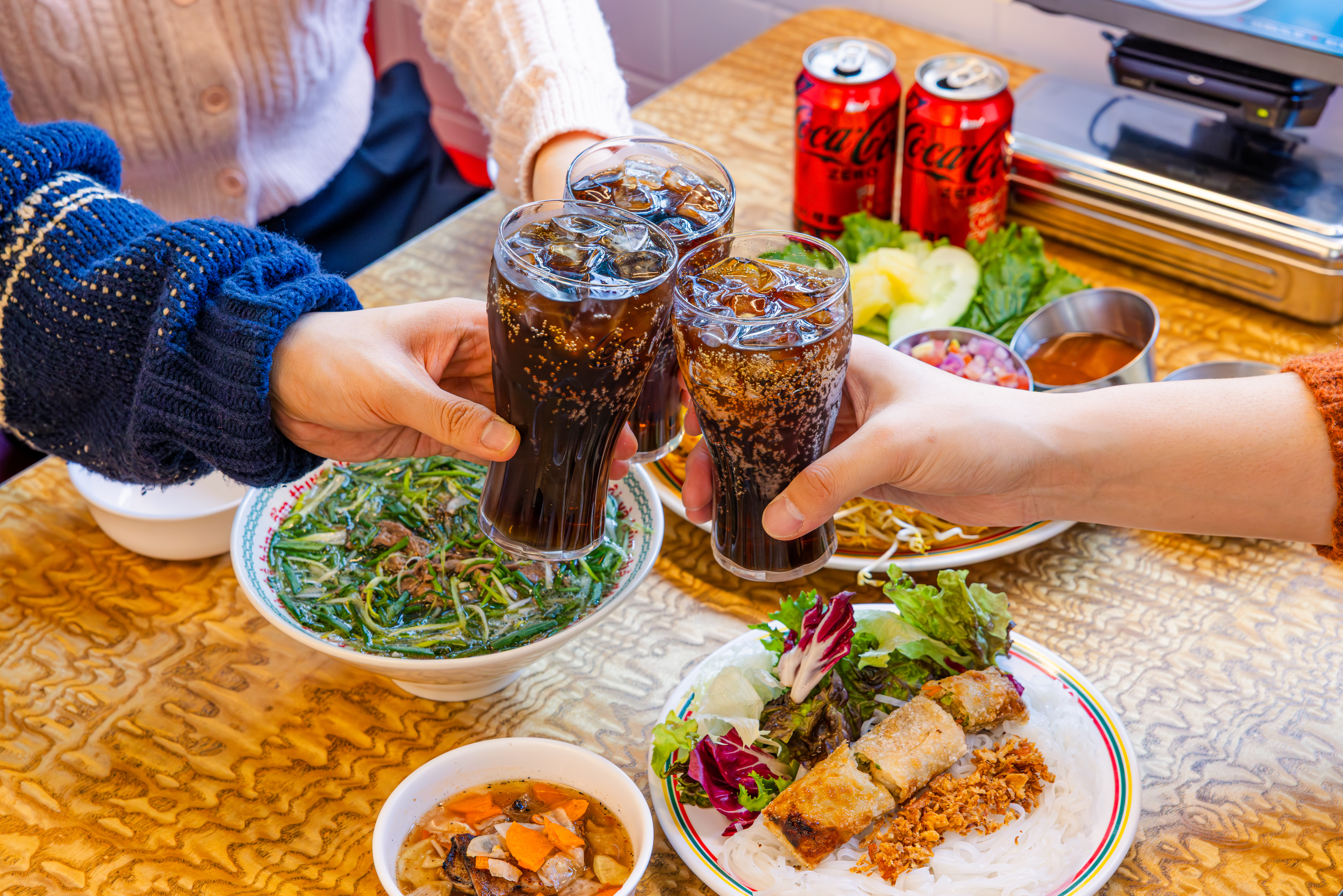 '꾸아 성수본점'의 대표메뉴, 한우사골직화칼국수, 1인 분짜, 냐짱반세오를 코카-콜라 제로와 함께 즐기고 있다.