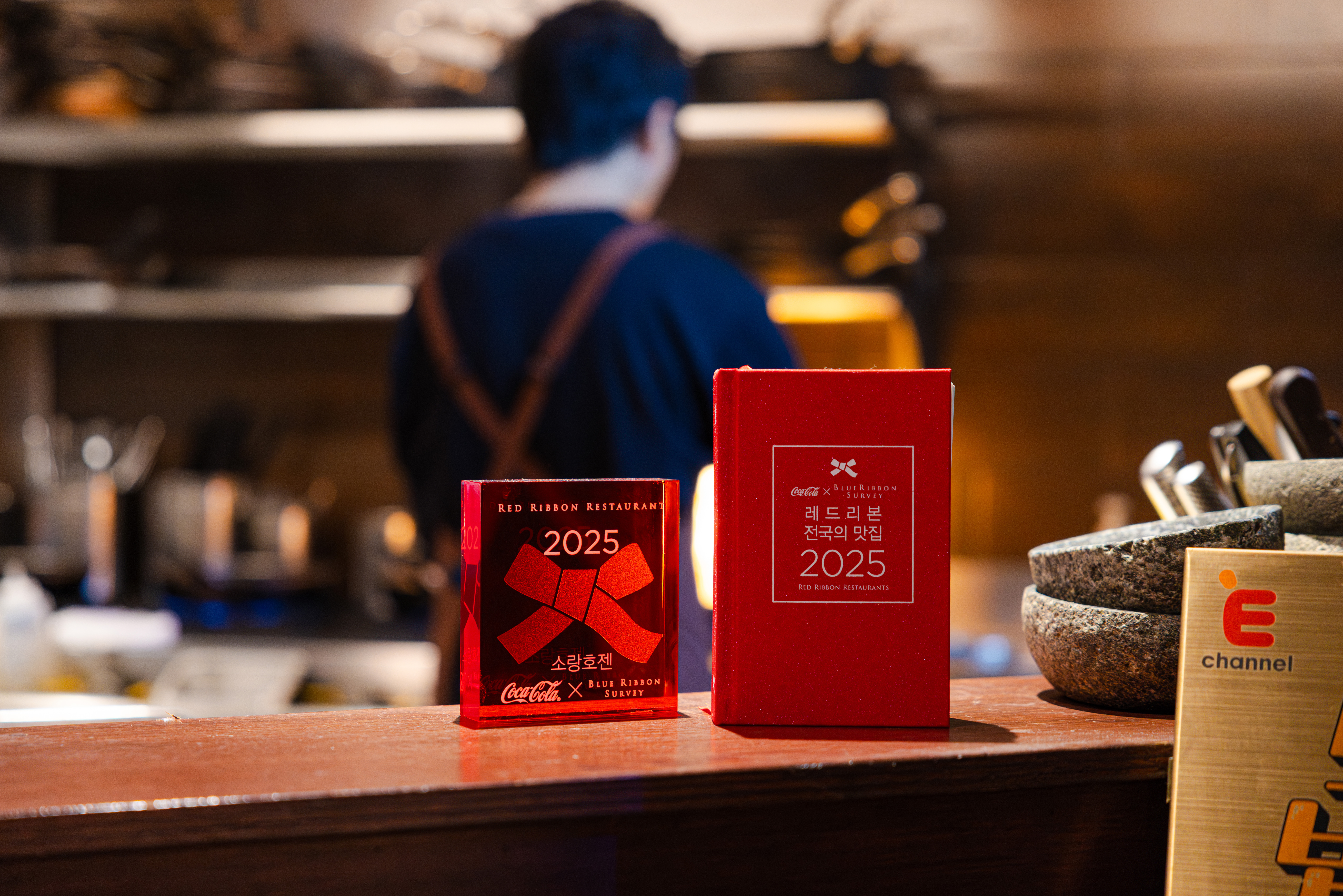 레드리본 맛집 인증을 받은 '소랑호젠'의 주방 테이블 위에 2025 레드리본 명패가 놓여져있는 모습