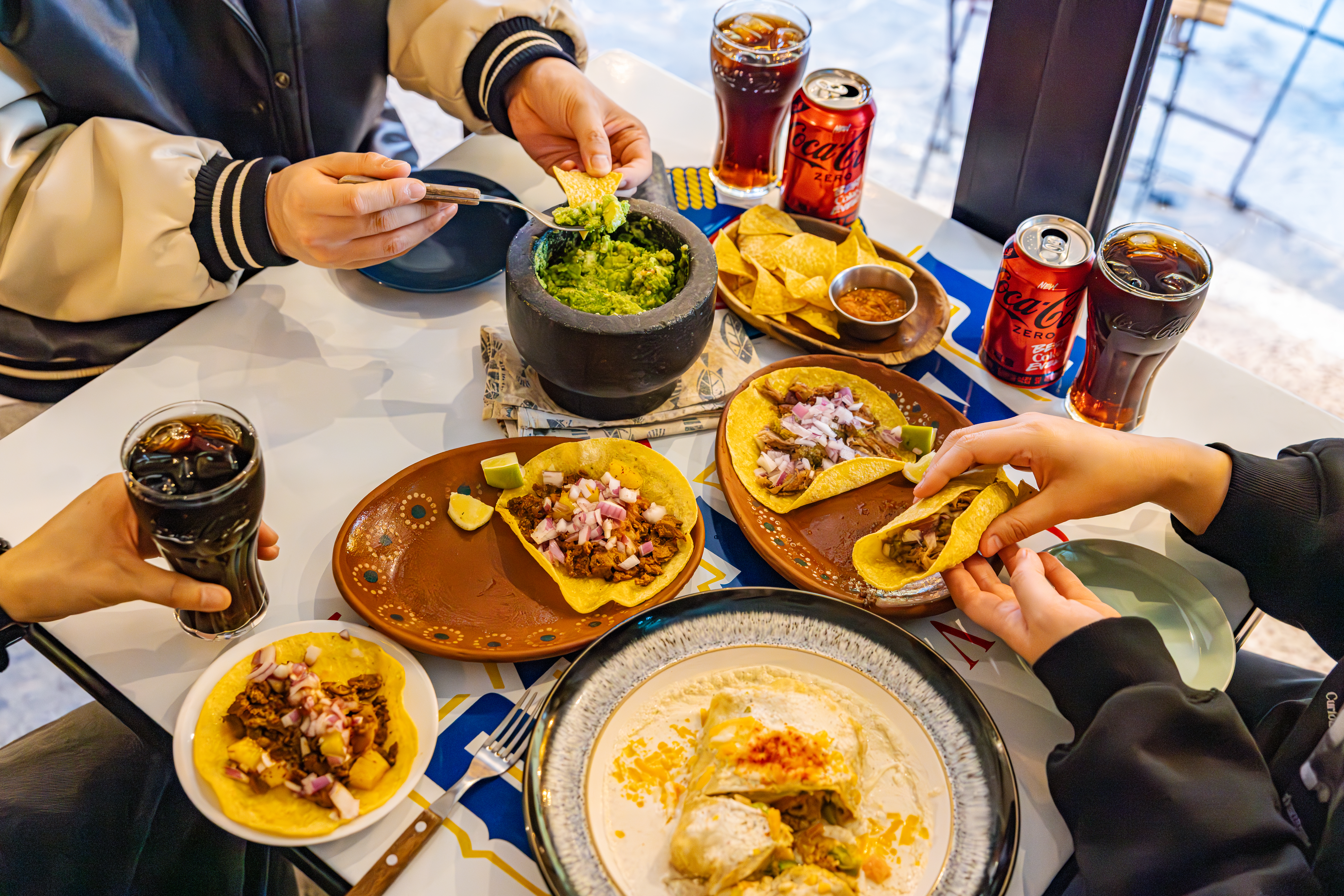 레드리본 맛집 '비아메렝게'의 대표메뉴, 카르니타스 타코, 프레쉬 과카몰리, 그리고 엔칠라다를 코카-콜라 제로와 함께 즐기고 있다.