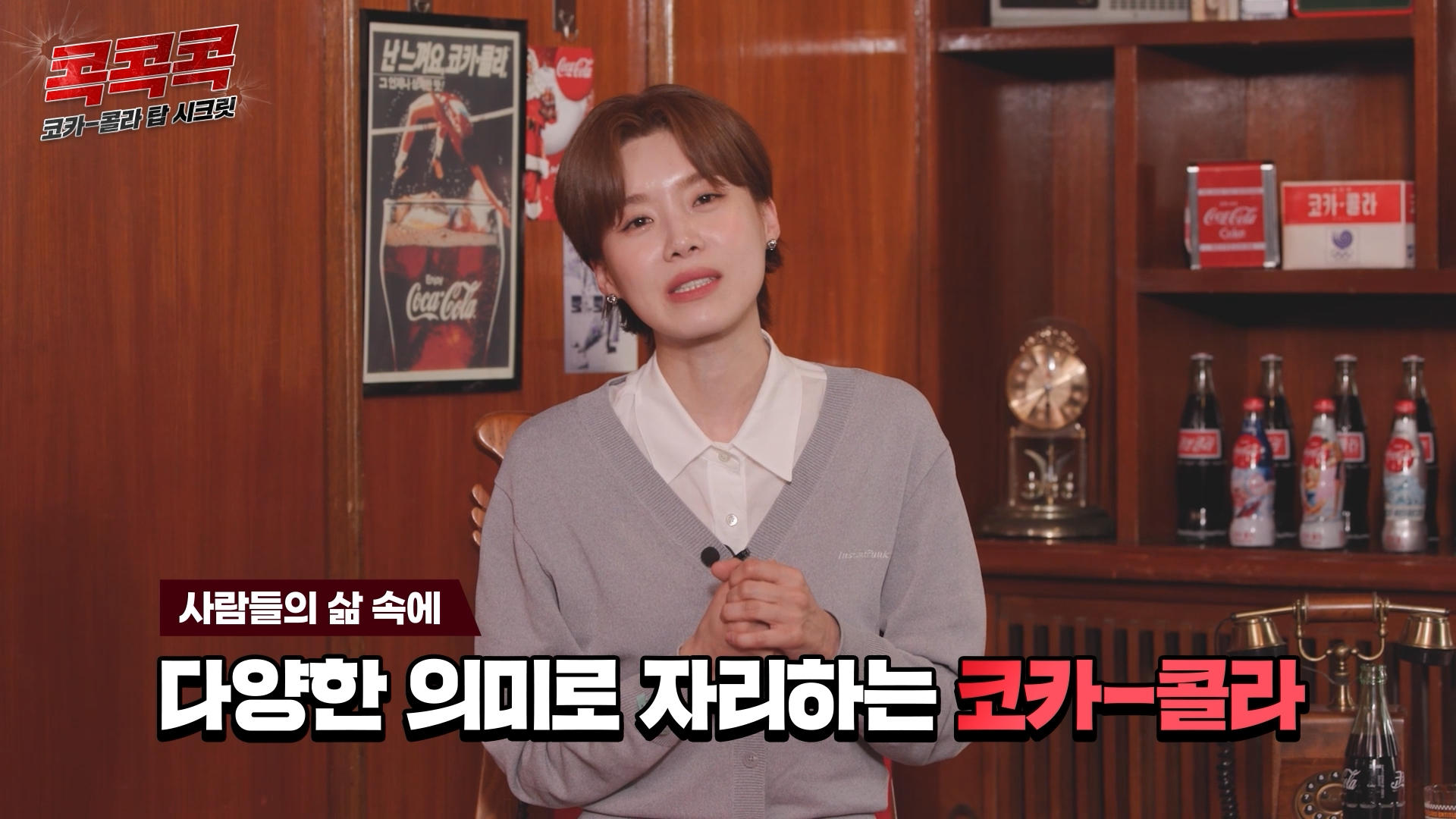 콕콕콕 12화 유튜브 영상 캡쳐본이다. 장도연이 두 손을 잡고 카메라를 응시하고 있다. 자막에는 사람들의 삶 속에 다양한 의미로 자리하는 코카-콜라라는 말이 적혀있다.