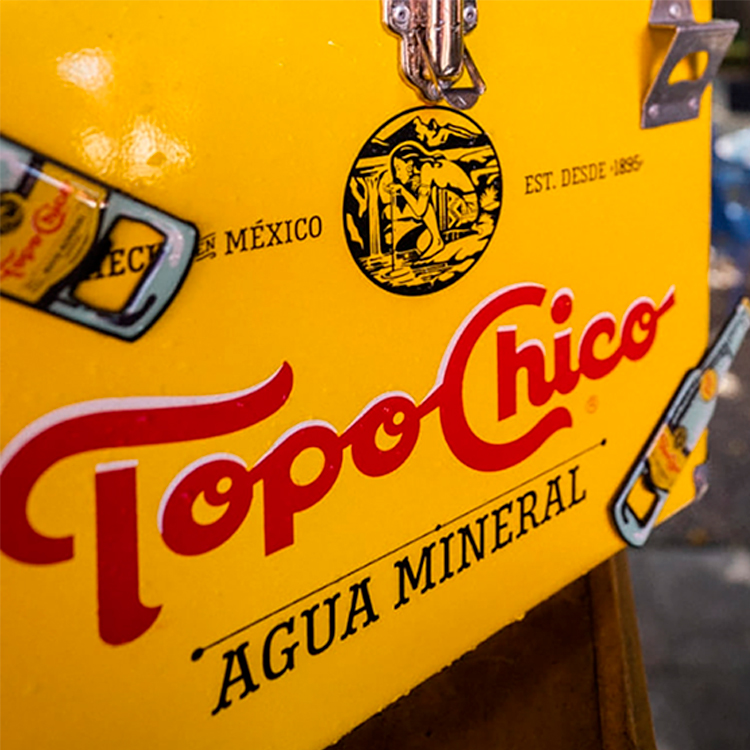 Primer plano de un refrigerador amarillo con la inscripción "Topo Chico" en color rojo.