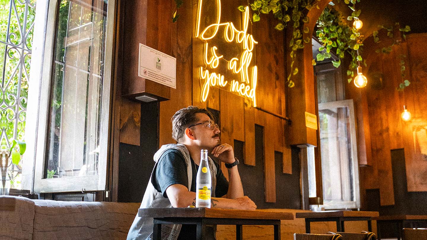 Hombre sentado en Dodo Café junto a una botella Topo Chico