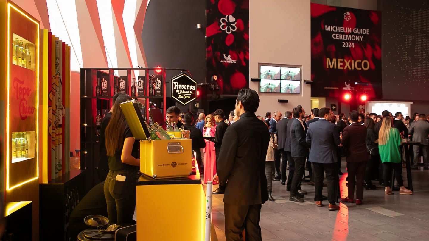 Stand de Topo Chico en el evento. De fondo se observan personas vestidas de forma elegante.