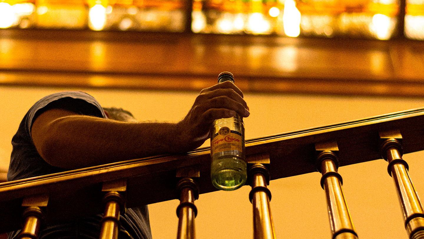 Hombre subiendo escalera, sosteniendo botella de Topo Chico agua mineral