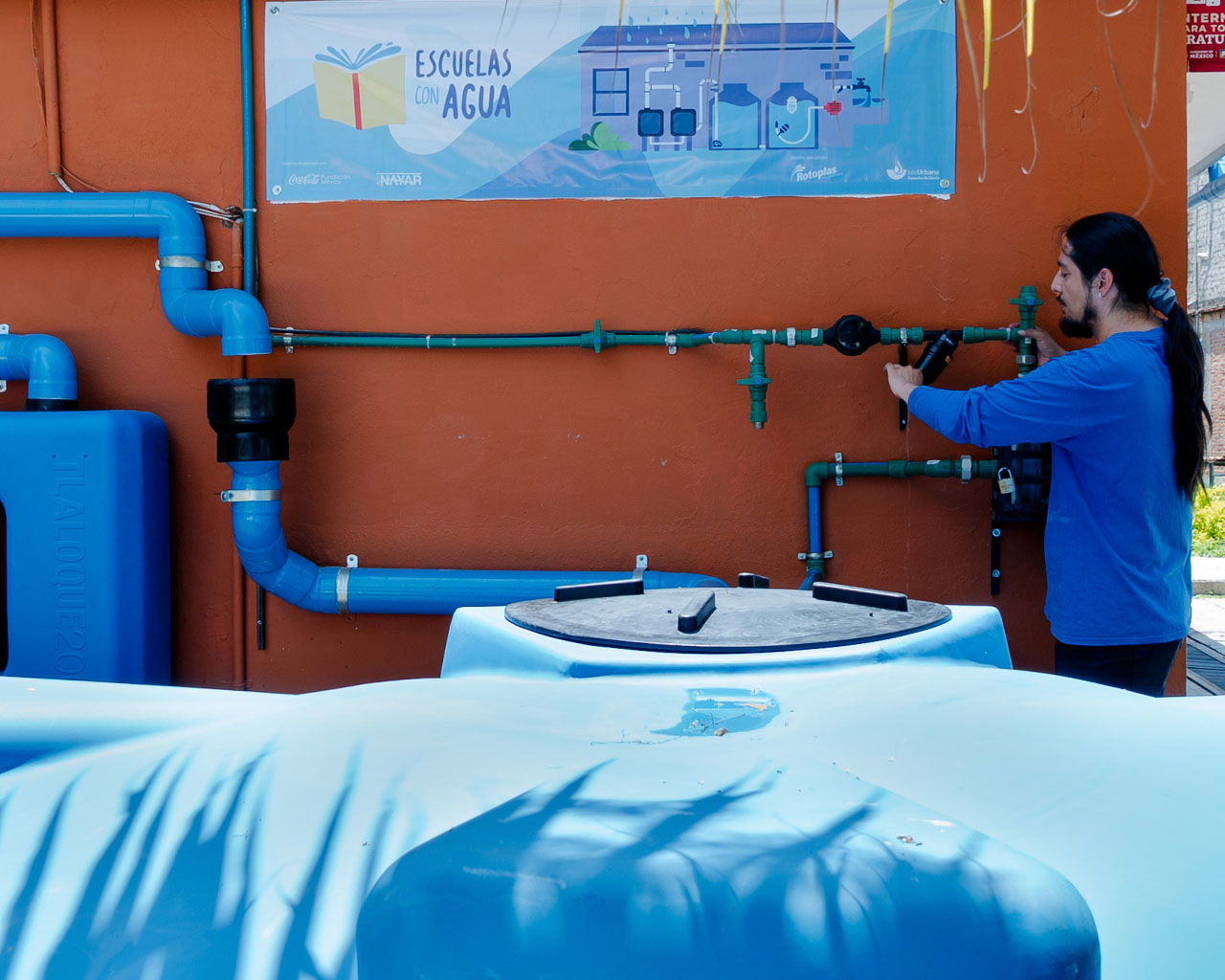 Persona cargando agua en un recipiente azul