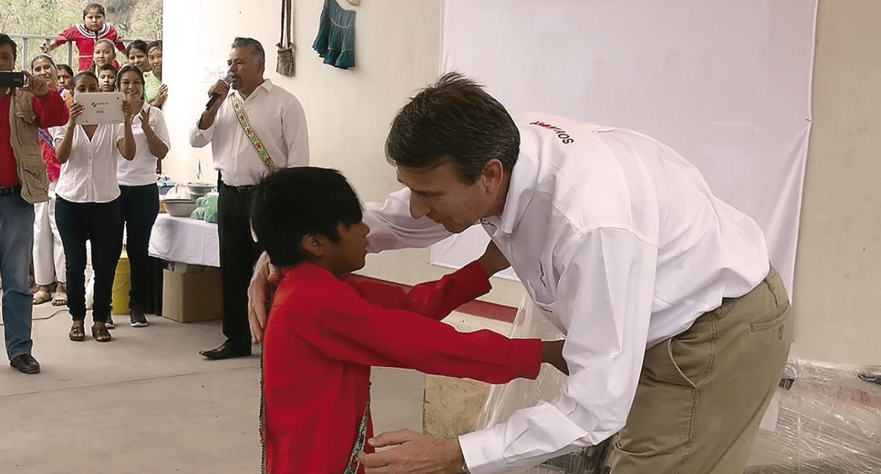 Hombre saluda a un niño en un evento, frente a la mirada de los presentes