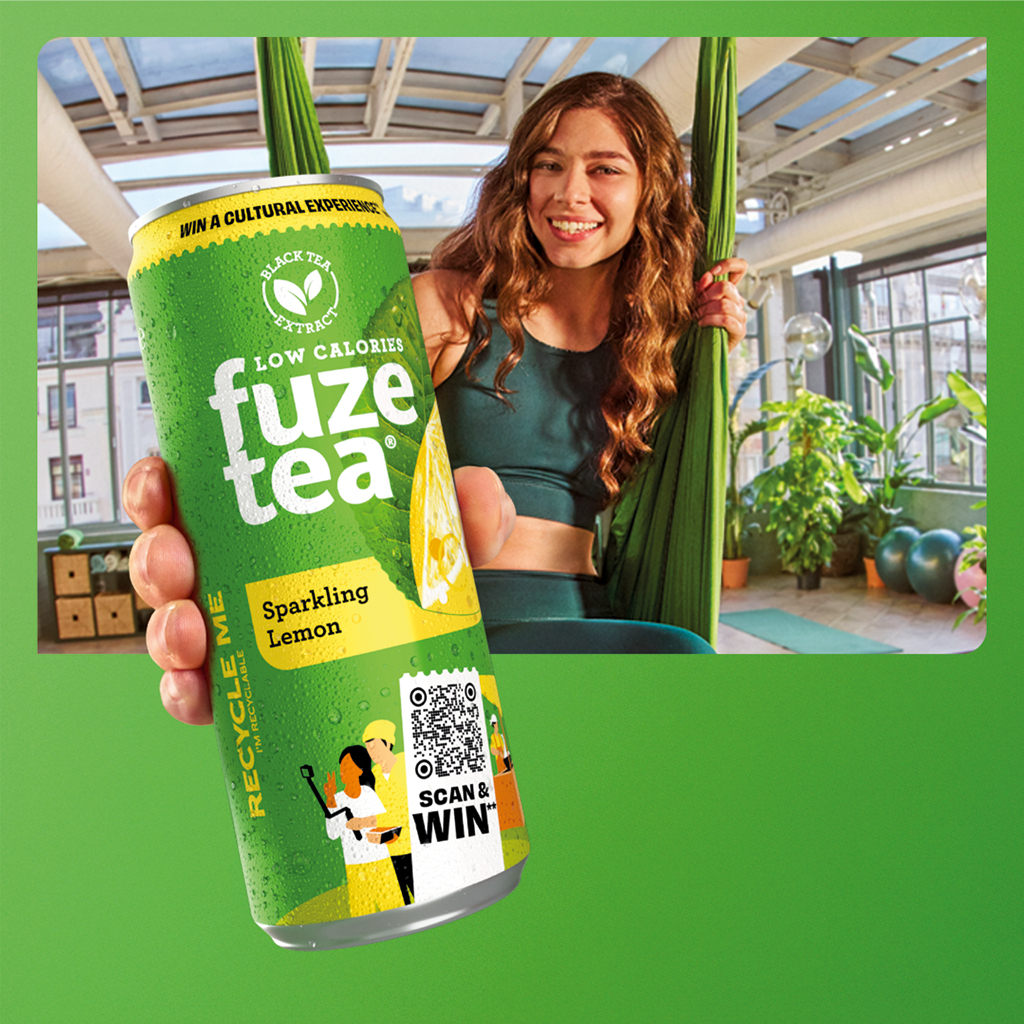 Persoon houdt een blikje Fuze Tea vast in een lichte fitnessruimte.