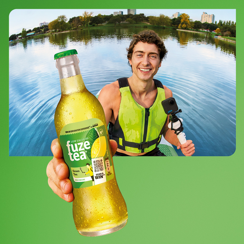 Persoon aan een meer houdt een fles Fuze Tea vast met een GoPro in de hand.