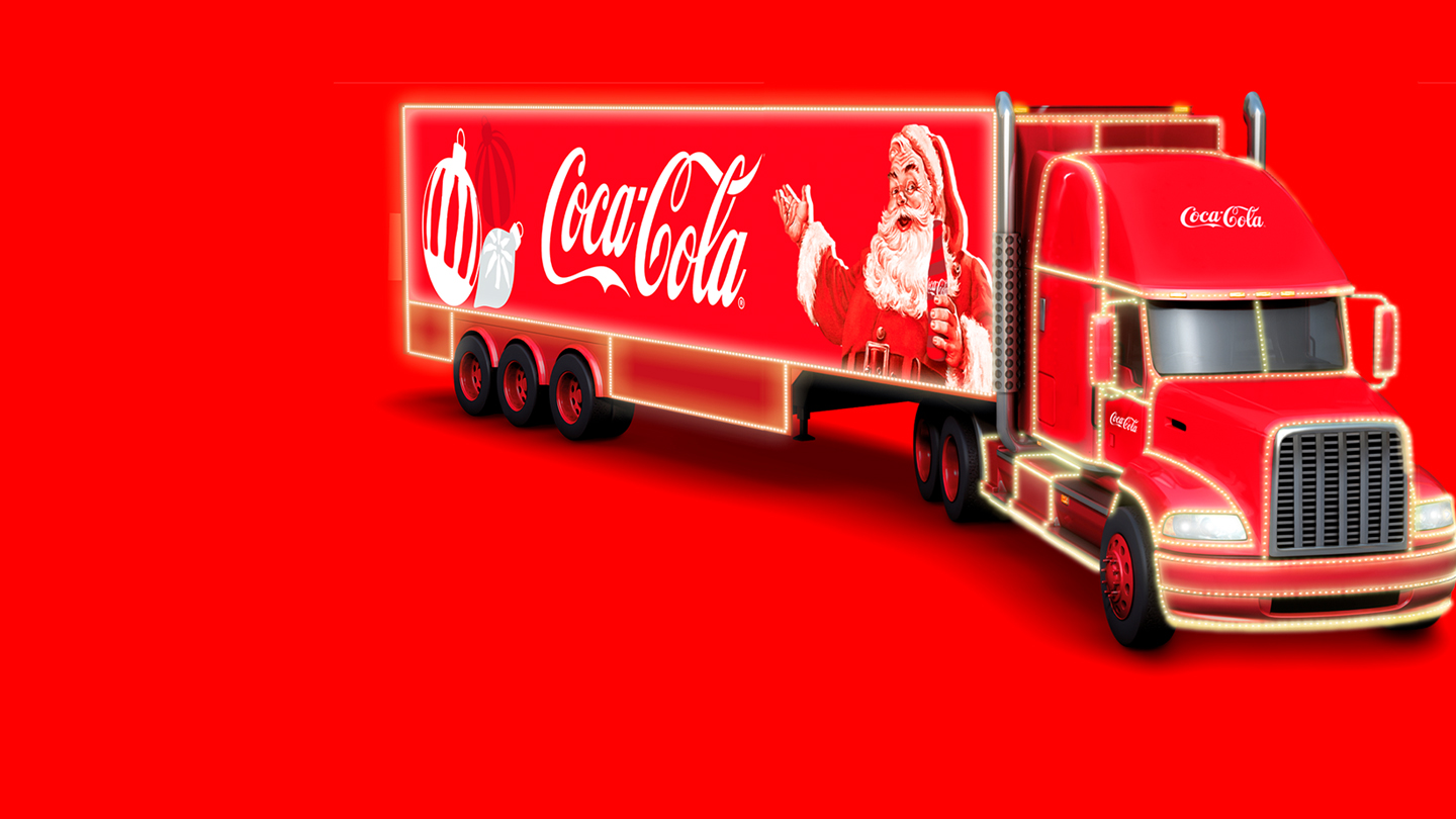 Imagen de un camión de Coca-Cola decorado con luces navideñas. El remolque muestra el logo de Coca-Cola y a Santa Claus sosteniendo una botella de Coca-Cola.