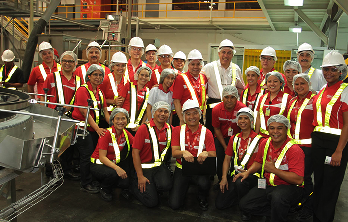 A group of Coca-Cola employees wearing Coca-Cola uniforms smiling 