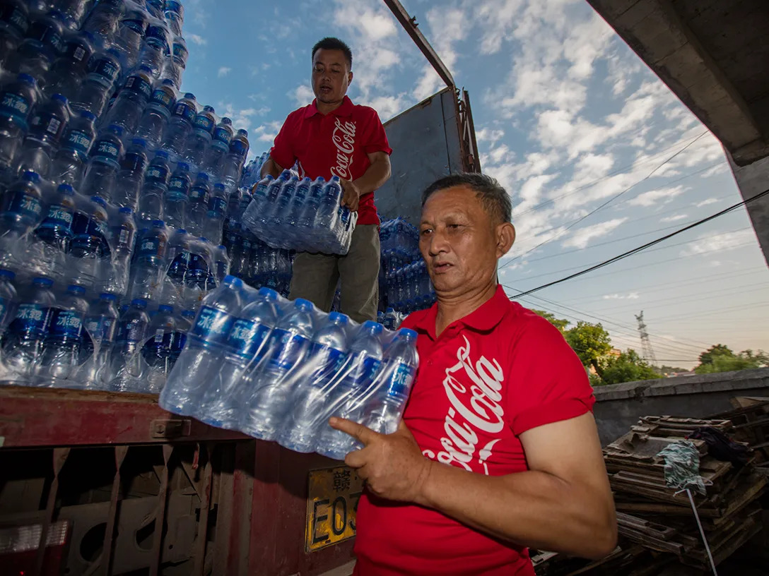 Two men unloading packages of bottled water from a truck