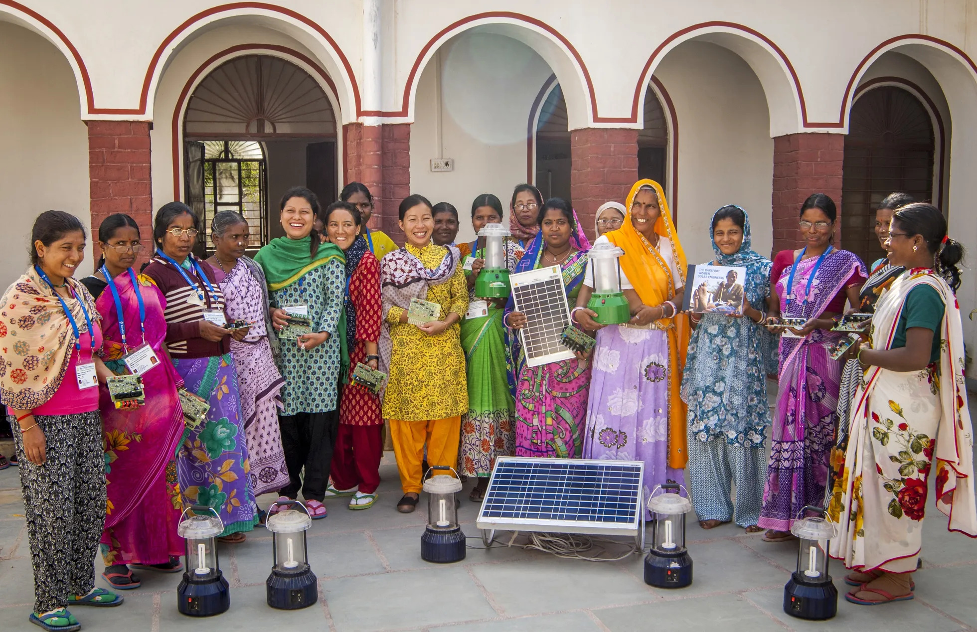 Group of women displaying solar cell panels, small circuits and electric lamps