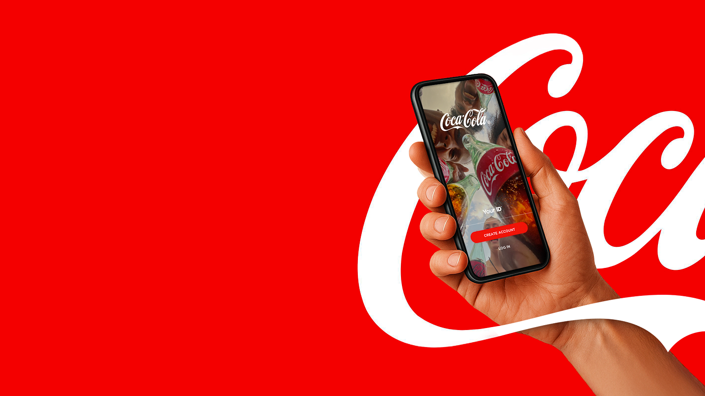 Mlada ženska sproščeno sedi na kavču, posluša glasbo s slušalkami in uporablja pametni telefon z aplikacijo Coca-Cola, ki ponuja nagrade, igre in digitalne vsebine