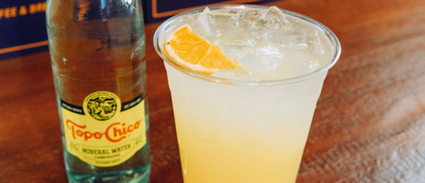 A bottle of Topo Chico next to a glass of Yuzu Sparkling Lemonade