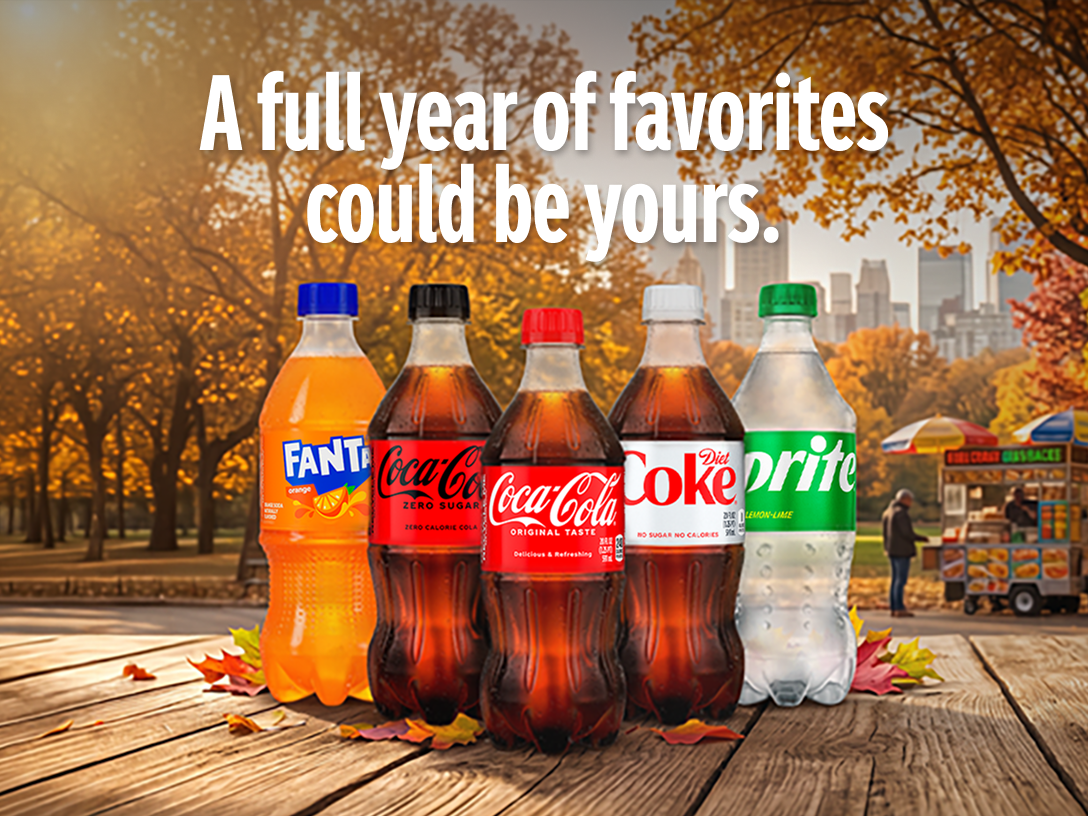 Assorted Coca-Cola products on an autumn park table promoting a sweepstakes to win a full year of favorites.