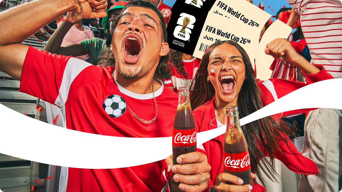 Dos aficionados emocionados en un estadio celebran con botellas de Coca-Cola y entradas para la FIFA World Cup 26™.