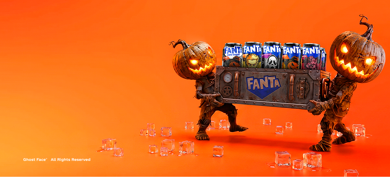 Two pumpkin-headed figures carry a metal Fanta crate filled with monster-themed Halloween cans on an orange background.